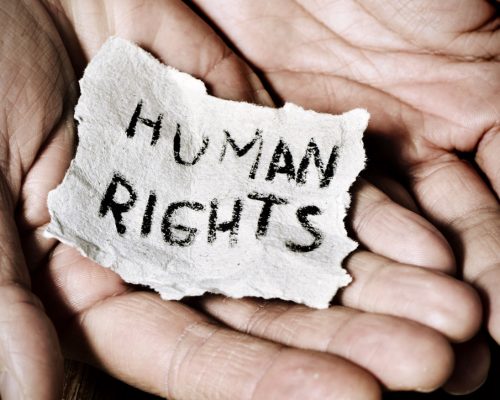 closeup of the hands of a young man with a piece of paper with the text human rights written in it, with a dramatic effect