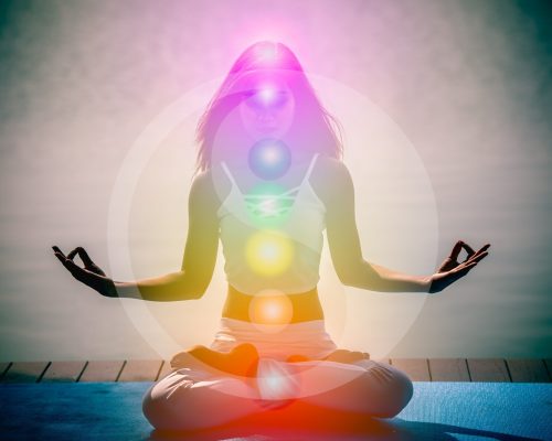 Young woman in yoga meditation with seven chakras and Yin Yang symbols.