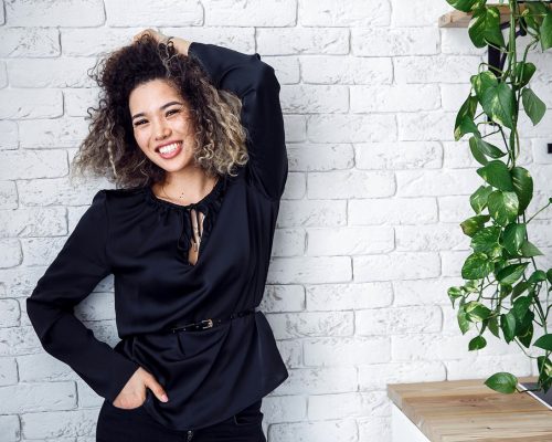 curly girl on a white brick background. happy girl in black.