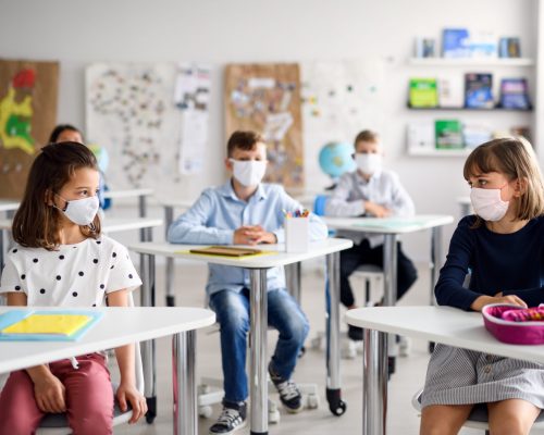 Small children with face mask back at school after covid-19 quarantine and lockdown.