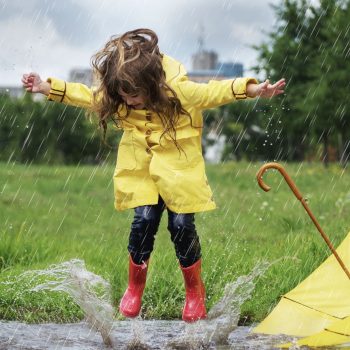 Happy child girl with an umbrella and rubber boots in puddle jump Happy child girl with an umbrella and rubber boots in puddle jump