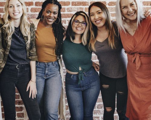 Cheerful diverse women standing in front of a red brick wall